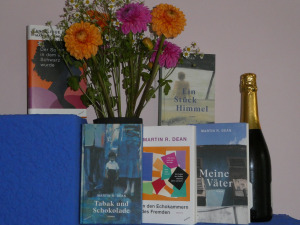 Foto von einem schönen Blumenstrauß, einer Flasche Sekt und fünf Büchern des Autors Martin R. Dean